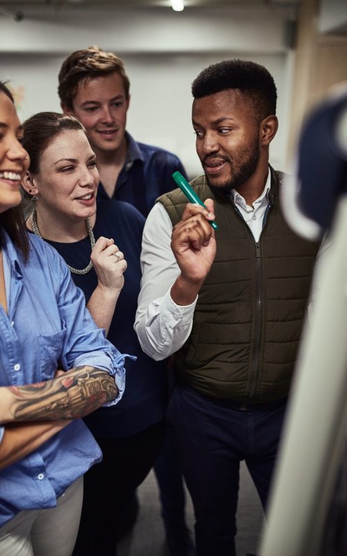 Shot of a group of designers brainstorming on a whiteboard in an office Shot of a group of designers brainstorming on a whiteboard in an office